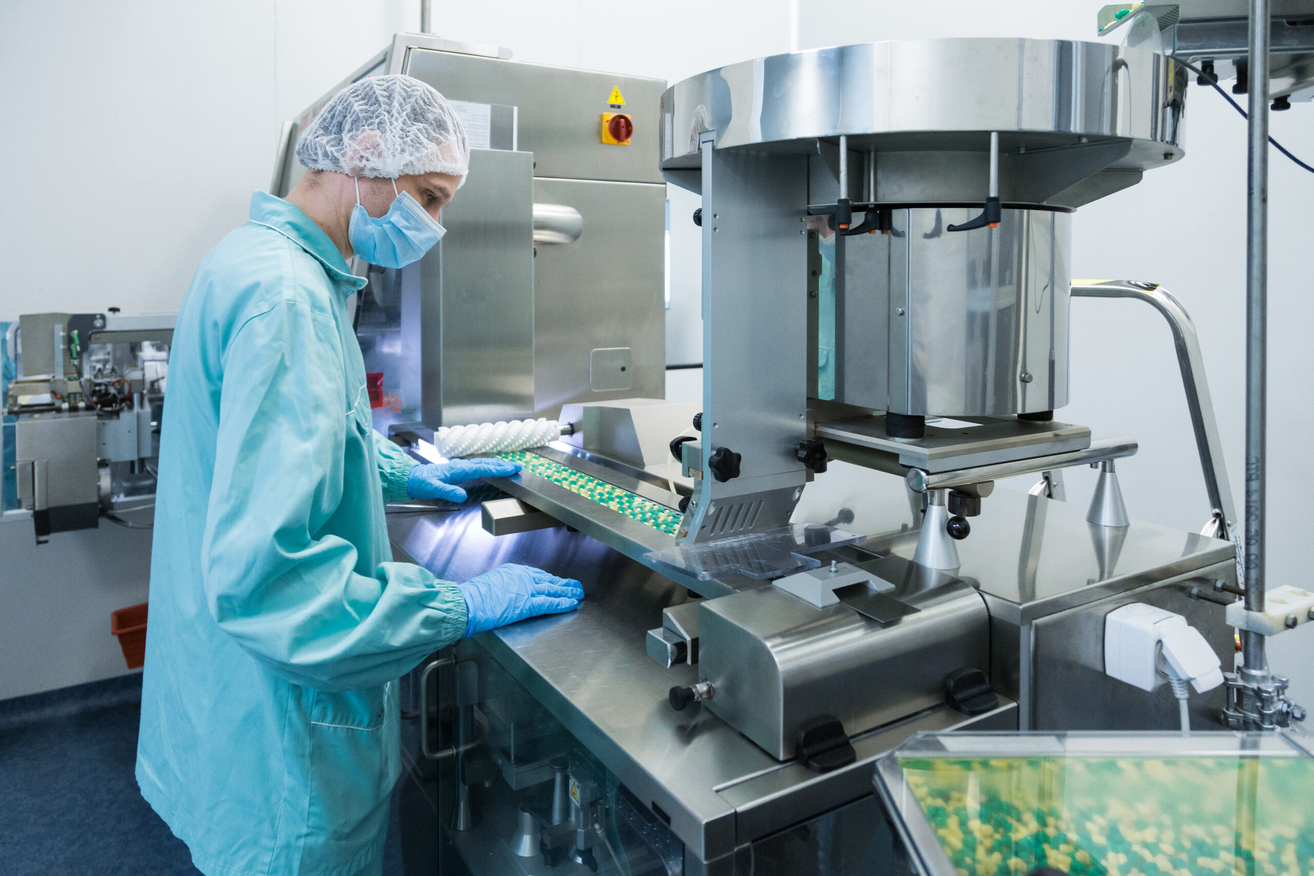 Pharmaceutical technician in sterile environment working on production of pills at pharmacy factory